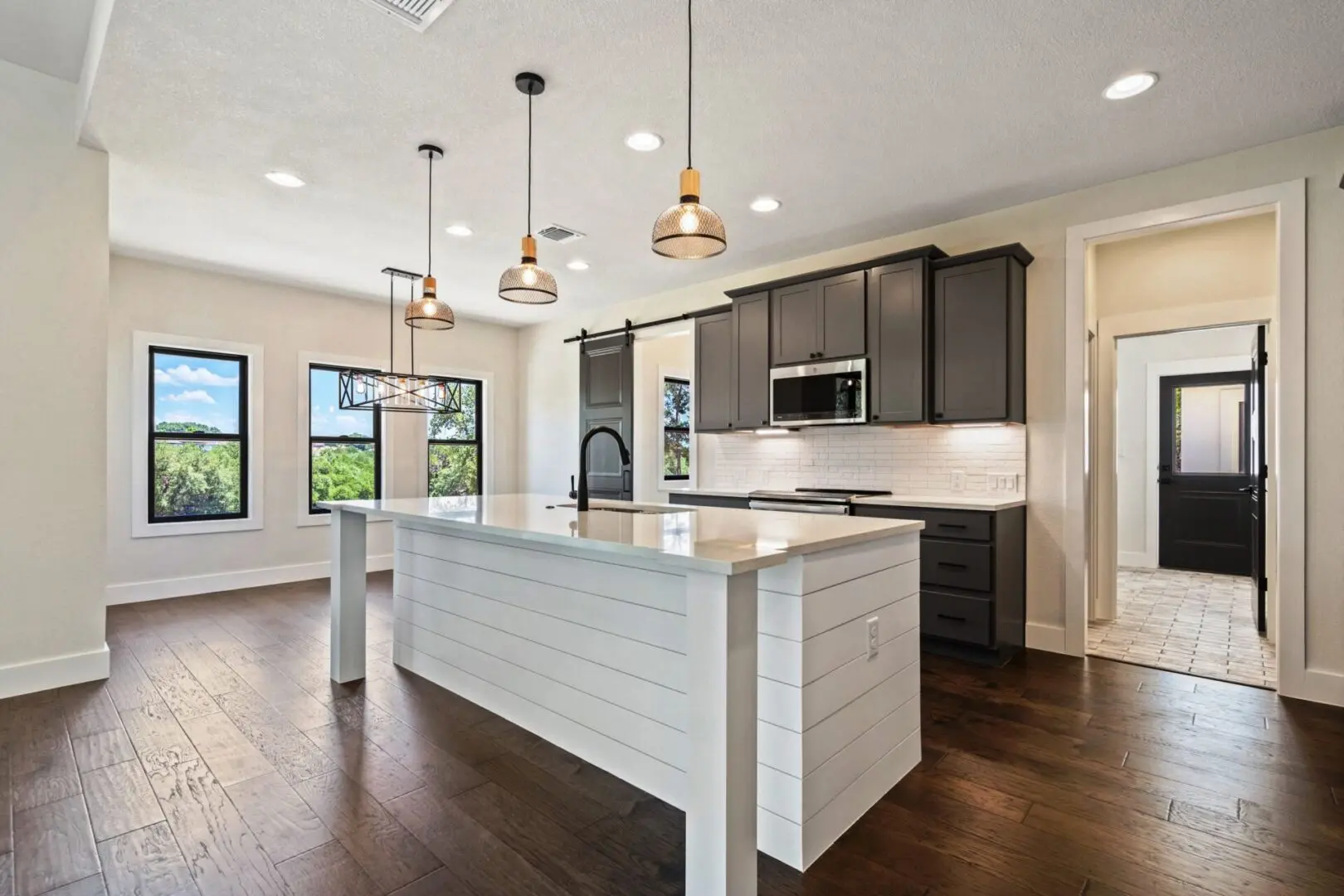 A kitchen with dark wood floors and white cabinets.
