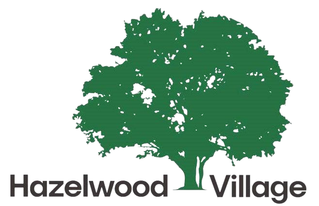 A green tree with the words hazelwood village underneath it.
